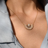 Necklace with a circular pendant worn by a person, with a blurred background