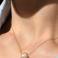 Close-up of a person wearing a gold earring and necklace.