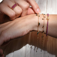 Person wearing multiple bracelets on a wrist with a blurred background