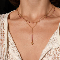 Close-up of a necklace with a pendant on a person wearing a lace garment.
