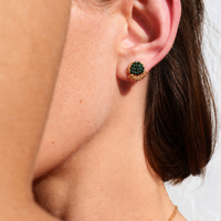 Close-up of a person wearing a green earring with a blurred background