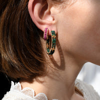 Close-up of a person wearing colorful hoop earrings with a blurred background