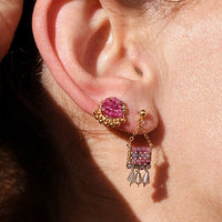 Close-up of a person wearing pink earrings with a neutral background
