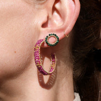 Close-up of a person wearing colorful hoop earrings with a neutral background