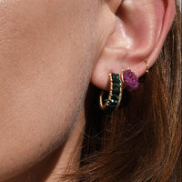 Close-up of a person wearing a necklace and earrings with a neutral background
