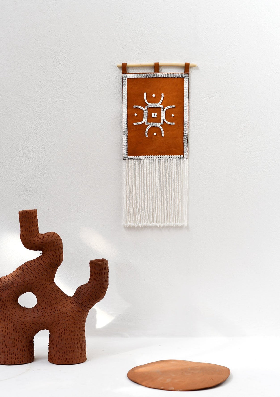 Maasai Leather beaded wall hanging feature Jan Ernst ceramic sculpture.