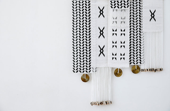 Assorted monochromatic modern African beaded decorative wall hangings with geometric shapes.