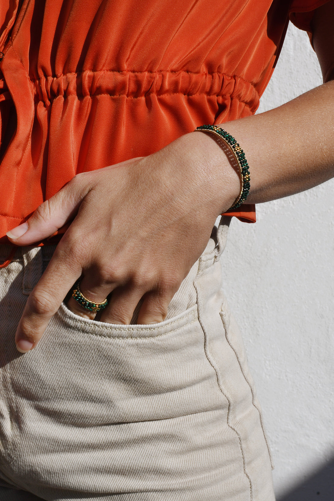 Person wearing an orange top and beige pants with a white background