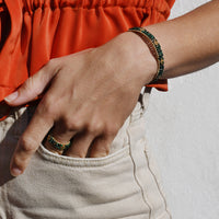 Person wearing an orange top and beige pants with a white background