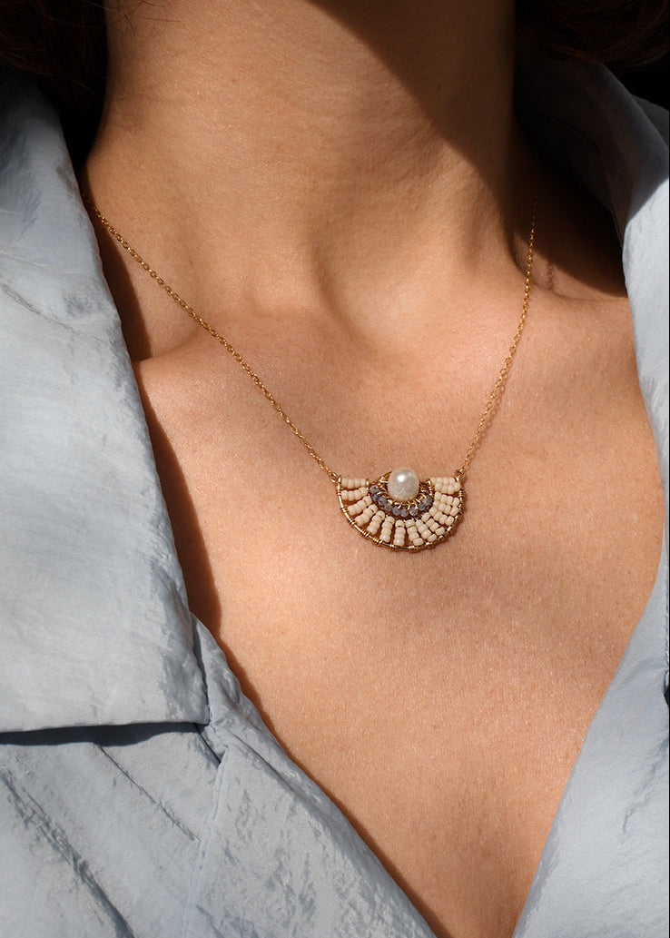 Necklace with a circular pendant worn by a person, with a blurred background