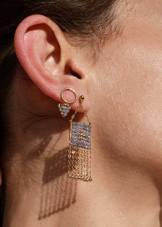 Close-up of a woman wearing gold fringe earrings and a delicate necklace.
