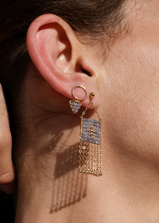 Close-up of a woman wearing gold fringe earrings and a delicate necklace.