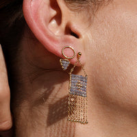Close-up of a woman wearing gold fringe earrings and a delicate necklace.
