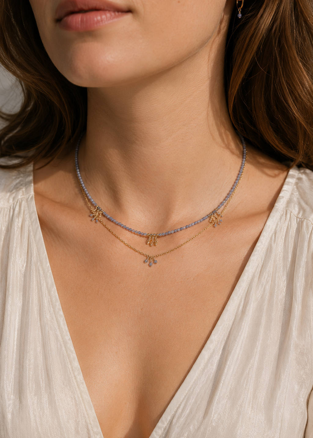 Close-up of a woman wearing a delicate necklace with a white top.