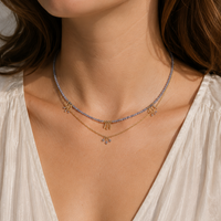 Close-up of a woman wearing a delicate necklace with a white top.
