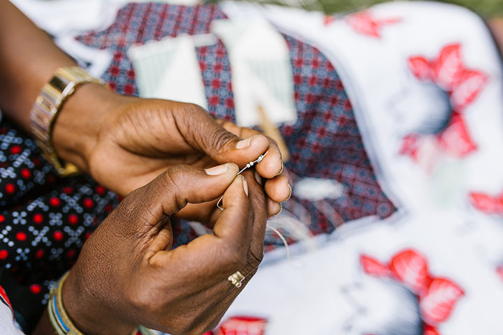 Maasai lady stringing hand beaded jewelry.