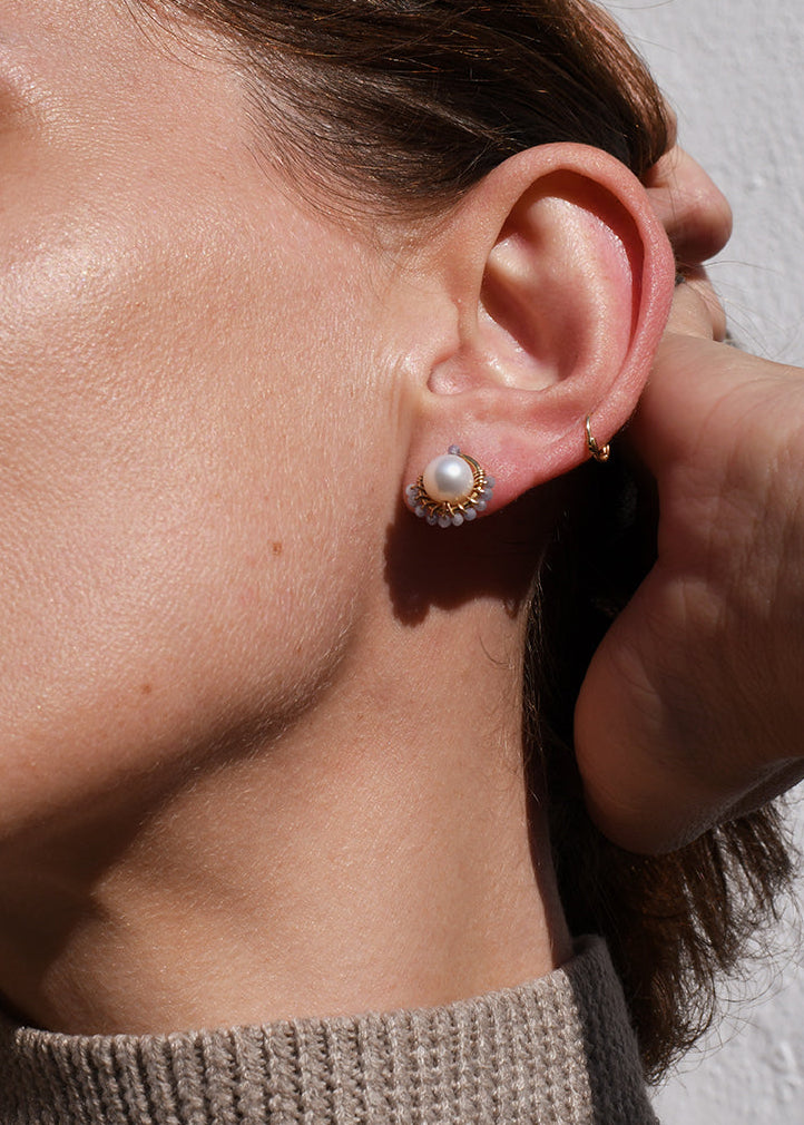 Close-up of a woman wearing pearl earrings with a neutral background