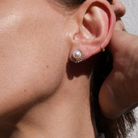 Close-up of a woman wearing pearl earrings with a neutral background