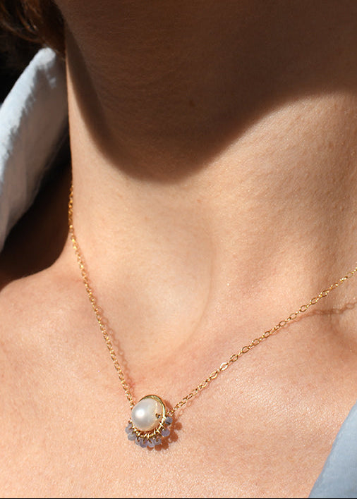 Close-up of a person wearing a gold earring and necklace.