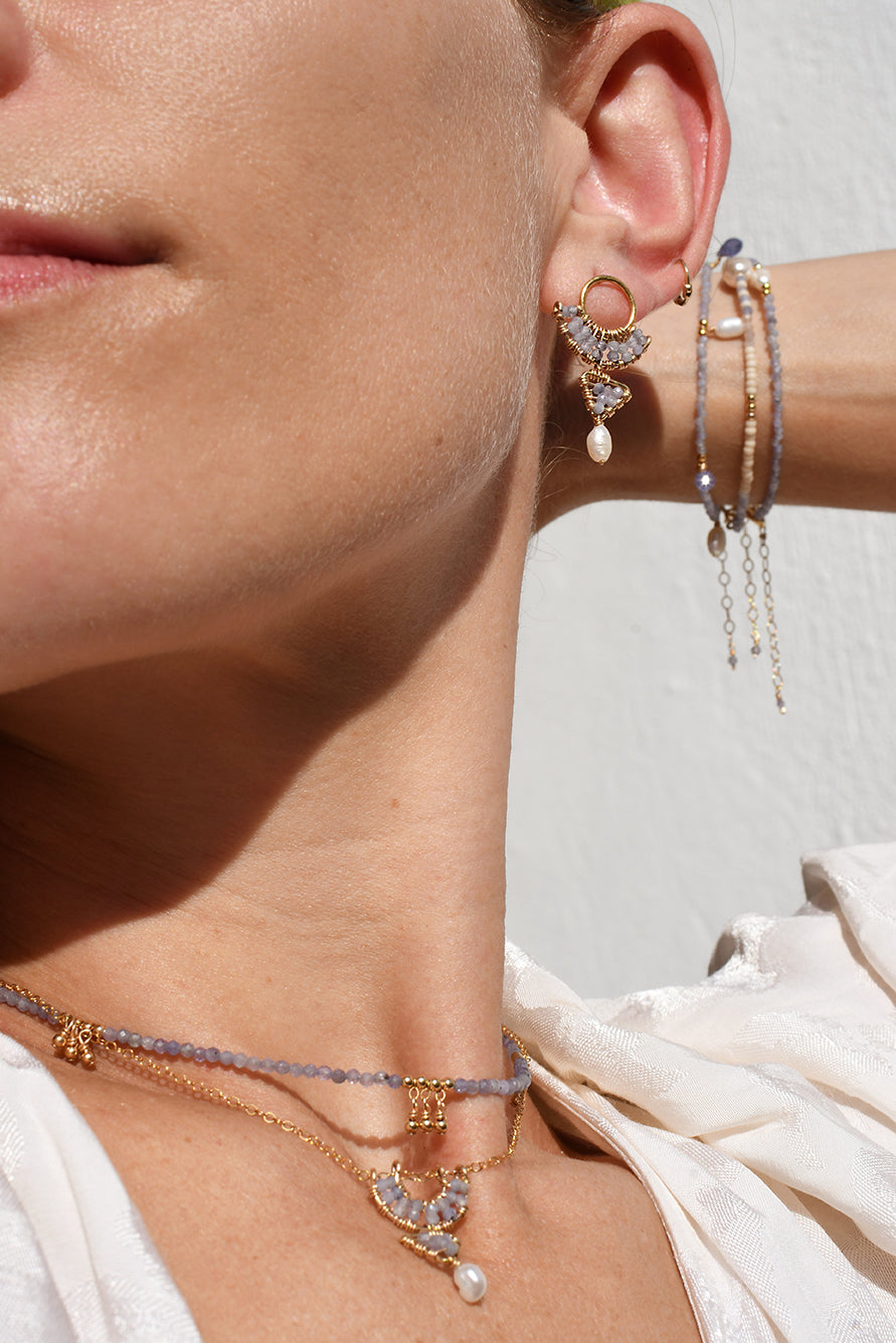 Close-up of a person wearing multiple earrings and necklaces with a blurred background