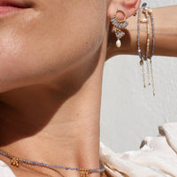 Close-up of a person wearing multiple earrings and necklaces with a blurred background