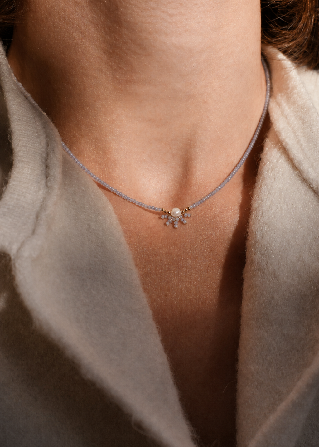Necklace with a pendant worn by a person, close-up on neck and shoulders.