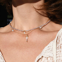 Close-up of a woman wearing multiple necklaces with a blurred background