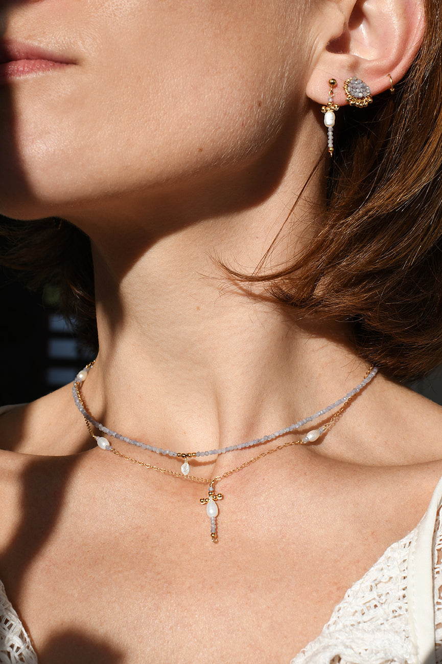 Close-up of a person wearing a necklace and earrings with a blurred background