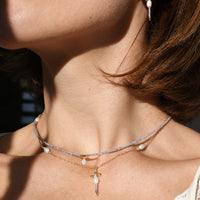 Close-up of a person wearing a necklace and earrings with a blurred background