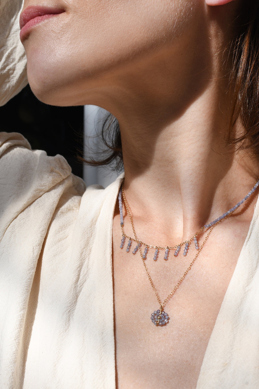 Close-up of a person wearing a delicate necklace with a pendant.