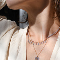 Close-up of a person wearing a delicate necklace with a pendant.