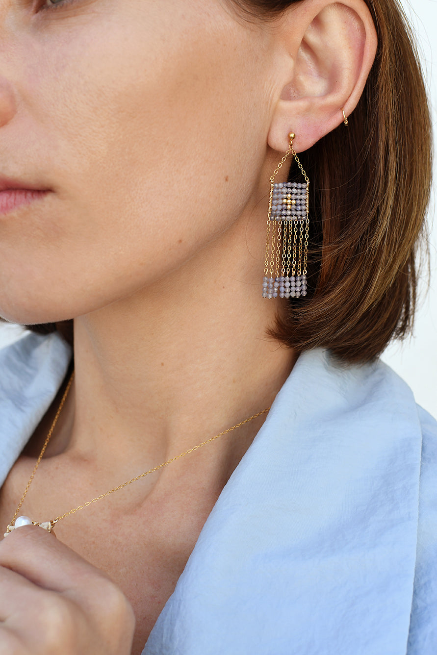 Close-up of a person wearing a diamond earring with a light blue shirt.
