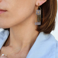 Close-up of a person wearing a diamond earring with a light blue shirt.