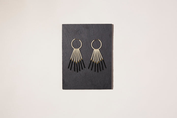 Pink black and gold statement beaded hoop drop earrings on a piece of slate. 