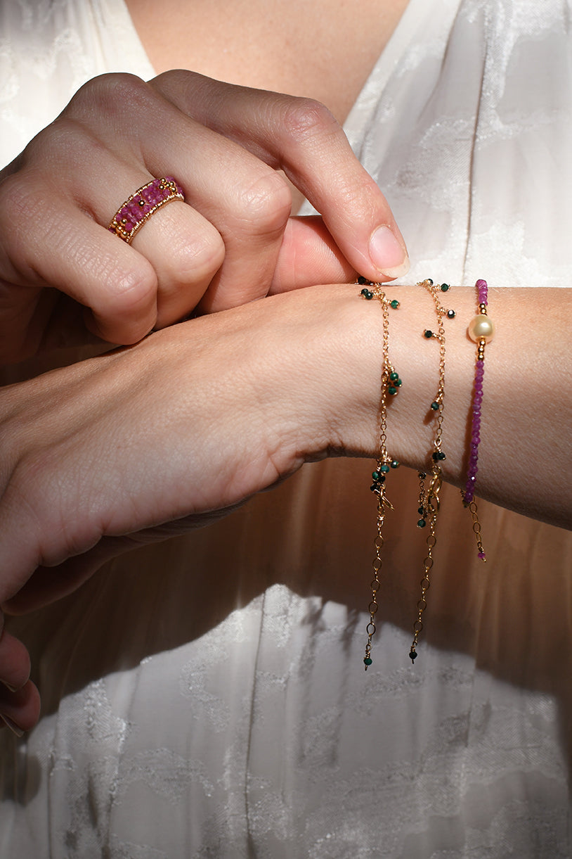 Person wearing multiple bracelets on a wrist with a blurred background
