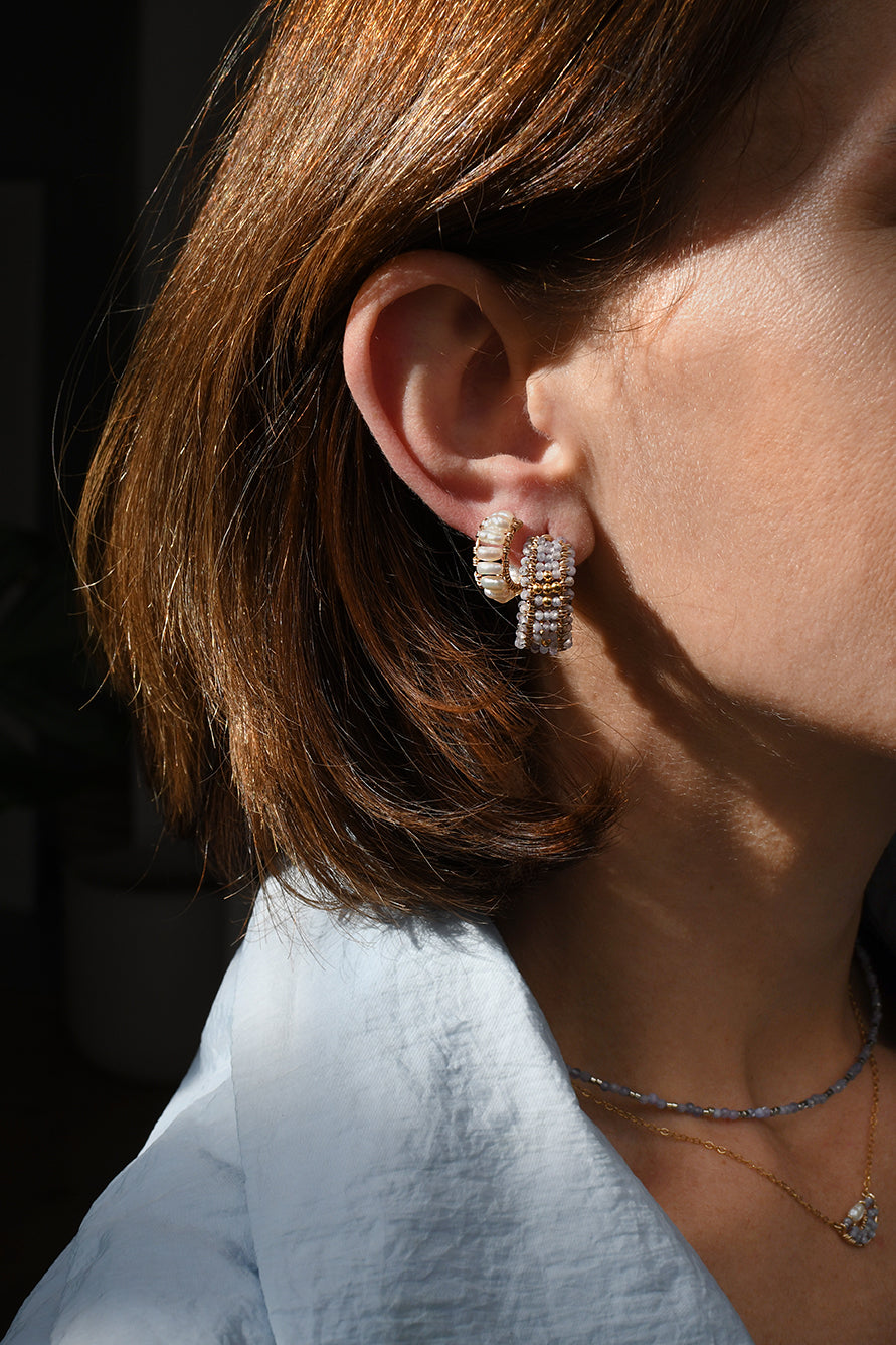 Close-up of a person wearing diamond earrings with a blurred background