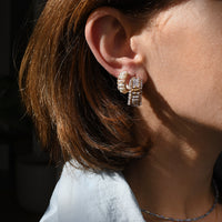 Close-up of a person wearing diamond earrings with a blurred background