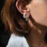 Close-up of a person wearing diamond earrings with a blurred background