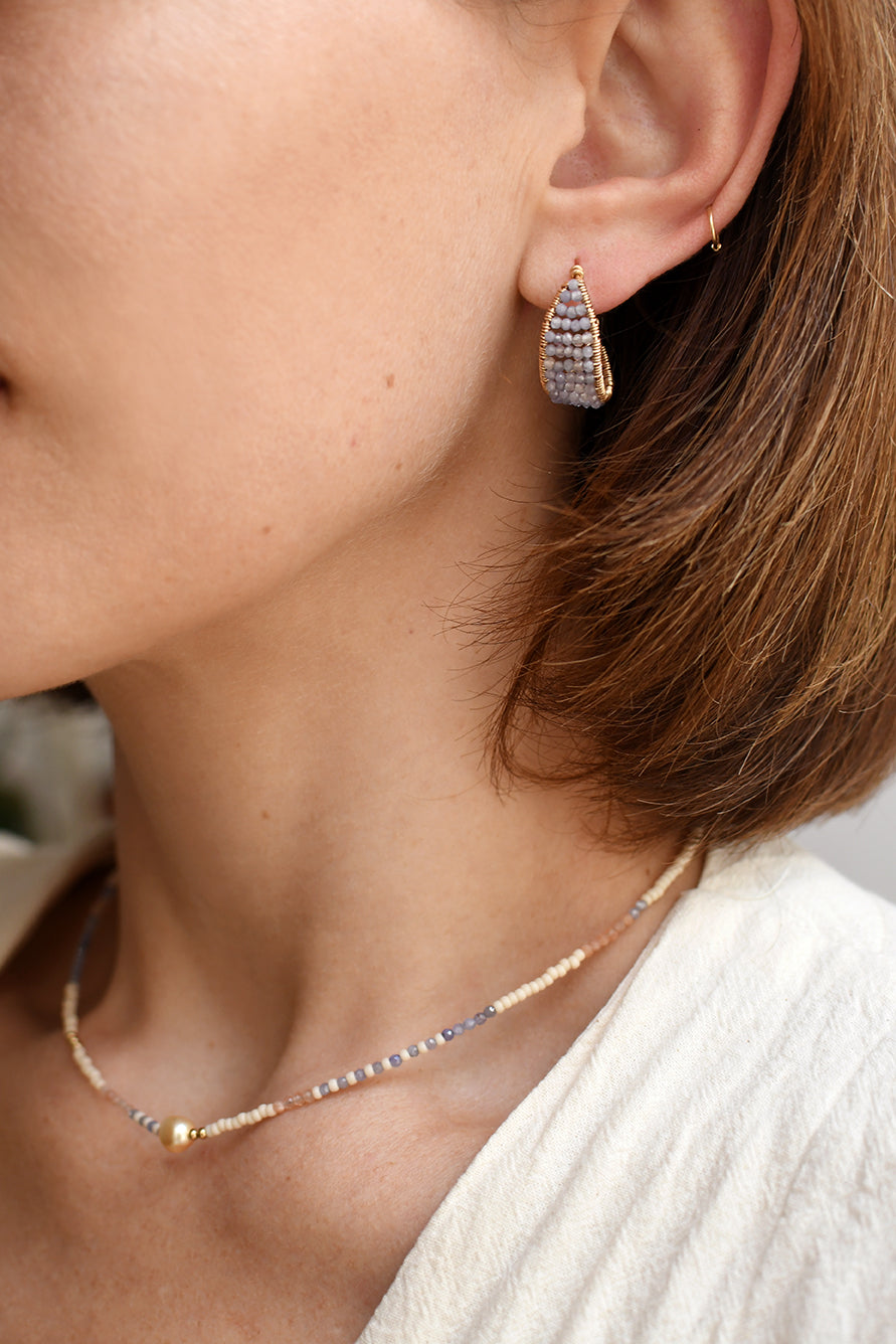 Close-up of a person wearing a necklace and earrings with a blurred background