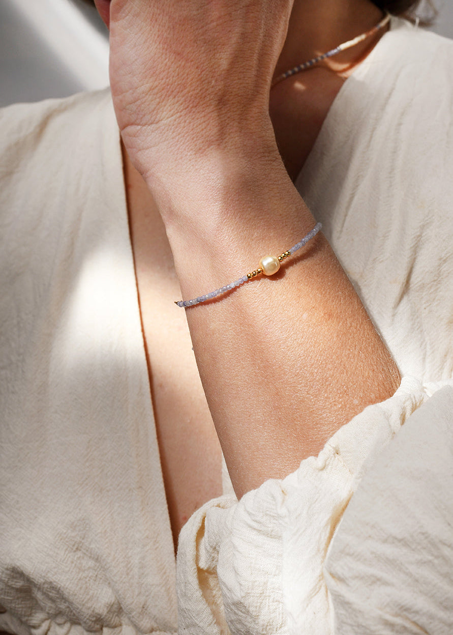 Close-up of a person wearing a delicate bracelet on a light background
