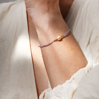 Close-up of a person wearing a delicate bracelet on a light background