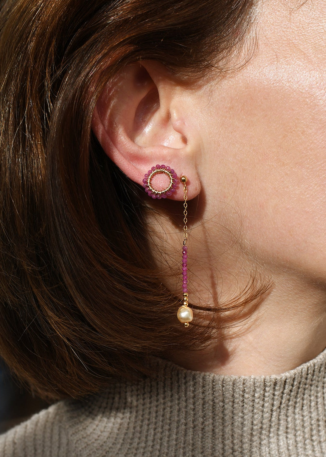 Close-up of a person wearing pink earrings with dangling beads.