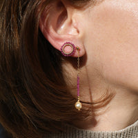 Close-up of a person wearing pink earrings with dangling beads.