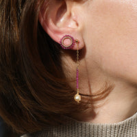 Close-up of a person wearing pink earrings with dangling beads.