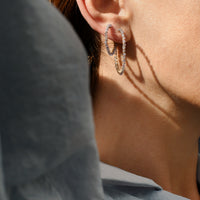 Close-up of an ear wearing a silver hoop earring with a blurred background