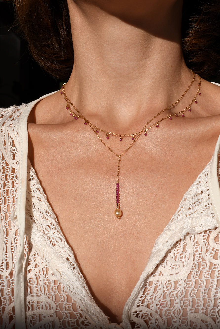 Close-up of a necklace with a pendant on a person wearing a lace garment.
