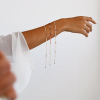Person wearing a delicate bracelet on a plain background