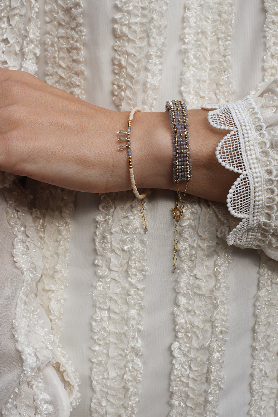 Close-up of a wrist wearing multiple bracelets with a textured white fabric background