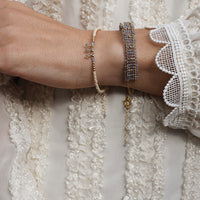 Close-up of a wrist wearing multiple bracelets with a textured white fabric background