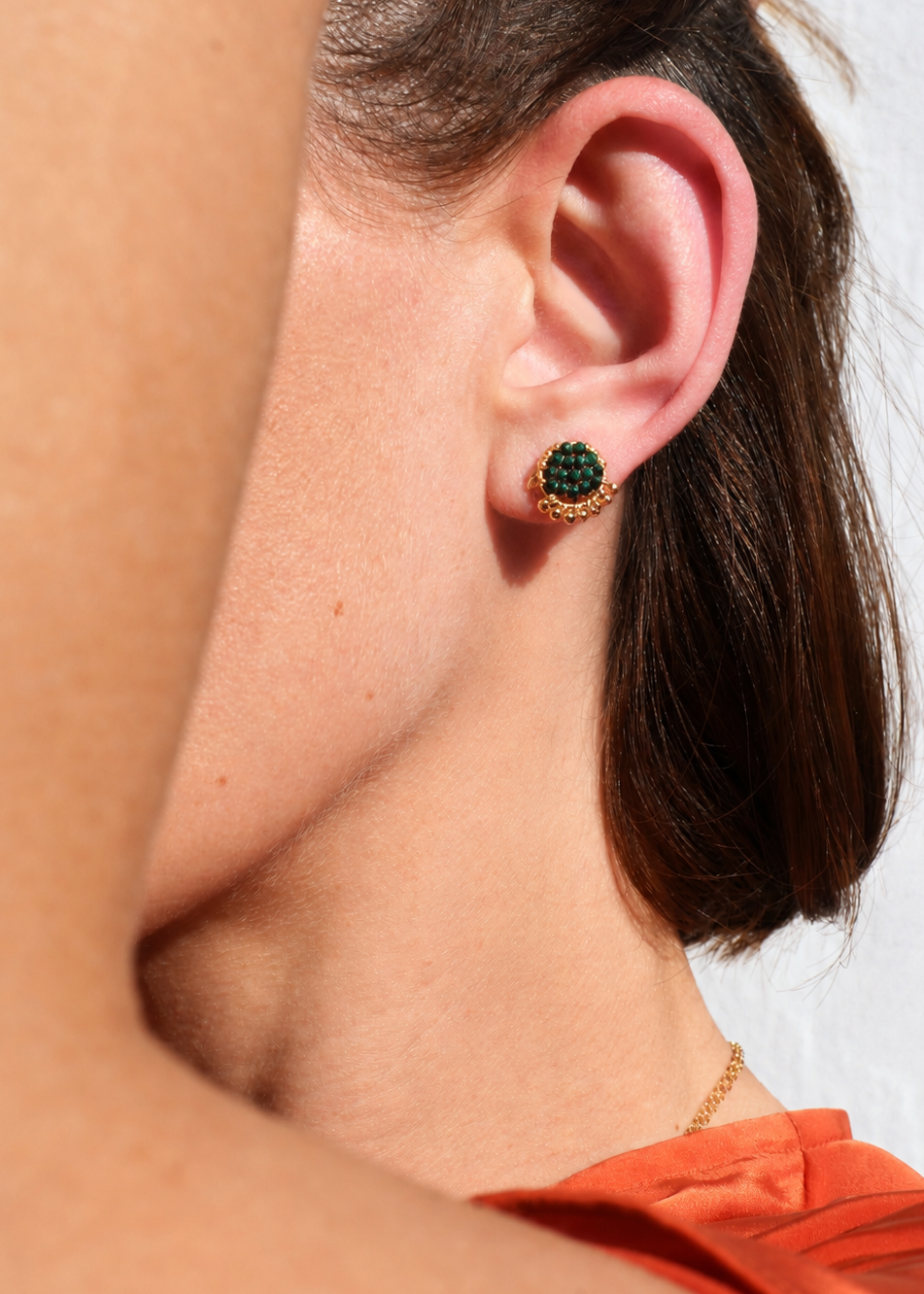 Close-up of a person wearing a green earring with a blurred background